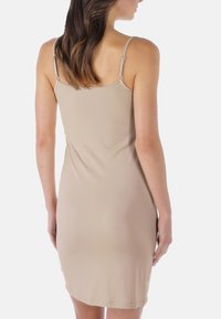 Abito aderente nudo con spalline sottili e lunghezza a metà coscia. Tessuto liscio con un design minimalista e senza fantasie.