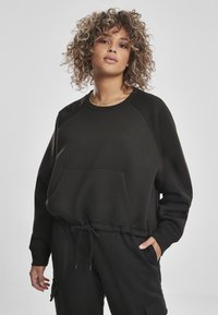 Felpa nera con colletto rotondo, maniche lunghe a raglan e tasca frontale. Presenta un orlo con coulisse e un tessuto morbido e texturizzato.