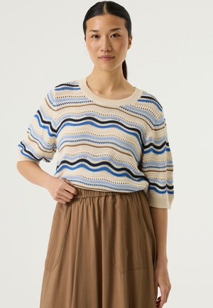 Suéter de punto con rayas onduladas en azul y tonos neutros, con mangas cortas y cuello redondo, combinado con una falda marrón con bolsillos.