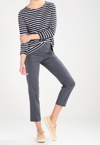 Námořnická a bílá pruhovaná košile s dlouhým rukávem spárovaná se šedými zkrácenými kalhotami a béžovými teniskami. Hladká tkanina s volným střihem.