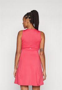 Pink sleeveless dress with a flared skirt, smooth texture, featuring a back zipper and subtle logo detail near the waist.