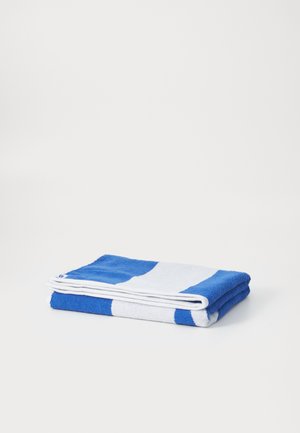 Serviette rayée bleue et blanche, de forme rectangulaire, fabriquée en coton texturé, soigneusement pliée avec des coutures visibles et une apparence douce.