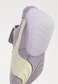 Purple sneaker with leather and suede materials. Features a textured rubber sole and contrasting cream accent along the side.