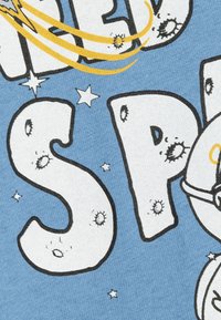 Tejido de algodón azul claro con llamativas letras en estilo de dibujos animados en blanco con contornos negros, estrellas espaciadas y acentos amarillos.