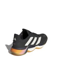 Scarpa sportiva nera con strisce bianche, superiore testurizzato, forma arrotondata e soletta con gradiente multicolore che va dall'arancione al trasparente.