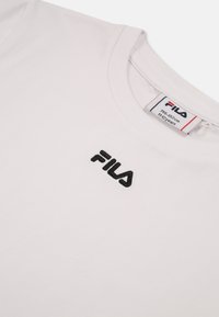 T-shirt bianco in cotone con logo "FILA" ricamato in nero sulla parte sinistra del petto. Collo rotondo e maniche corte.