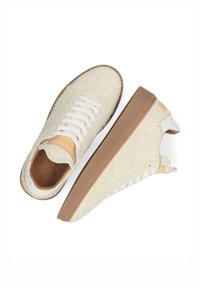 Kremowe, puszyste sneakersy z białymi sznurówkami i tanowymi gumowymi podeszwami, pokazane z góry i z boku na białym tle.