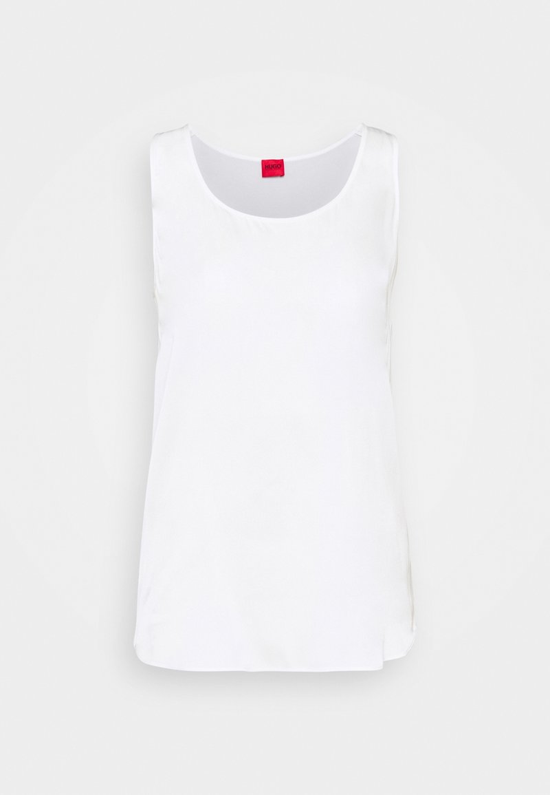 Débardeur blanc sans manches avec un col rond et une étiquette rouge de la marque à l’intérieur du col sur un fond clair uni.