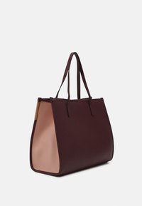 Tote-väska i vinröd och blekrosa. Tillverkad av ett slätt material med en strukturerad form, med två förlängda handtag och en gulddetalj.