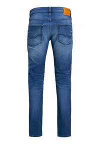 Blå denimjeans med slim fit, midjehöjd och två bakfickor. Tyget har en urtvättad look och en strukturerad känsla.