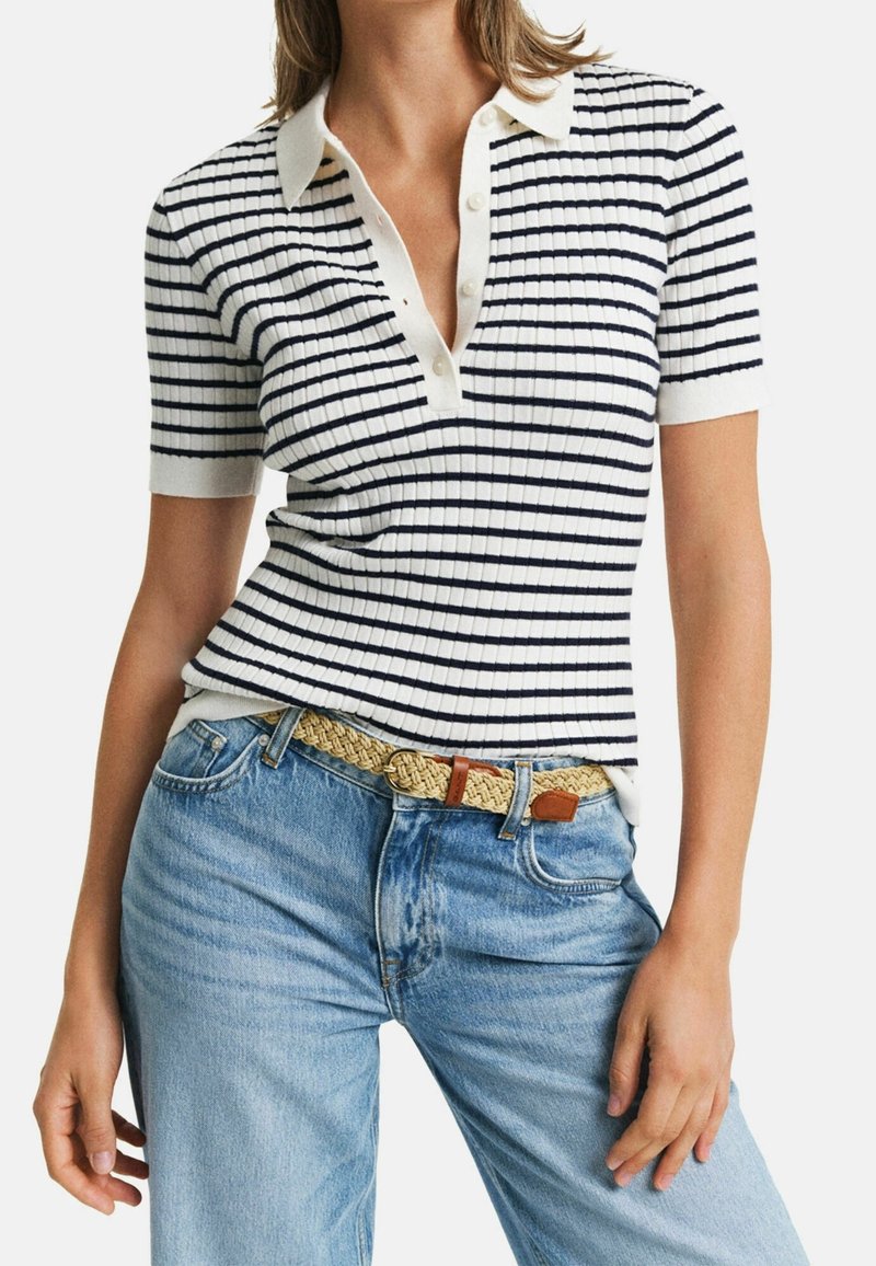 Polo w paski w kolorze białym i granatowym, z zapięciem na guziki i krótkimi rękawami, zestawiony z niebieskimi dżinsami o wysokim stanie i plecionym paskiem.