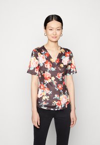 Top de manga curta com padrão floral em tecido escuro com decote em V, apresentando flores vermelhas, rosas e azuis. Textura suave com um ligeiro brilho.