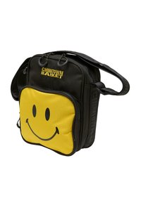 Sort stofpose med et gult smiley-ansigt på forsiden, der har en lynlåslomme og en skulderrem. "CHINATOWN MARKET" logo inkluderet.