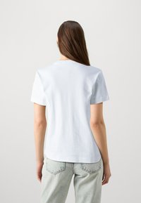 Šviesiai mėlynas medvilninis marškinėliai su apvaliu iškirpimu ir trumpomis rankovėmis, pasižymintis lygia danga ir atsipalaidavusia forma nugaroje.