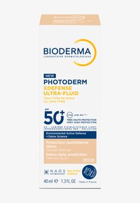Protezione solare Bioderma Photoderm XDefense Ultra-Fluid in confezione bianca. Caratteristiche SPF 50+, difesa ambientale e indicatore di tonalità beige. 40 ml.