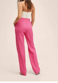 Pantalones de pierna ancha rosas con un patrón de lunares, cintura entallada y tela suave. Detalles adicionales incluyen bolsillos delanteros y un ajuste elegante.