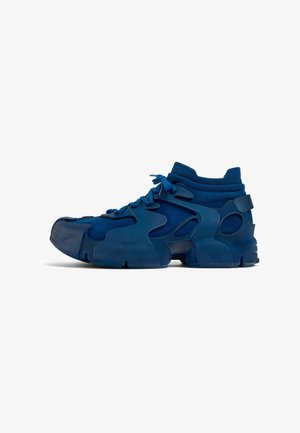 Zapatillas deportivas azules con una parte superior de tejido texturizado, acentos de goma moldeada, cuello alto y suela gruesa con secciones recortadas.