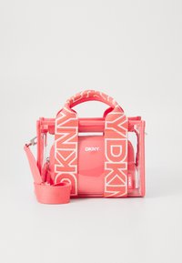 Koralen DKNY torba z prozorno telo, tekstilnimi trakovi s logotipom, zgornja ročaja in nastavljivim ramenskim trakom. Zapiranje z zadrgo je vidno.