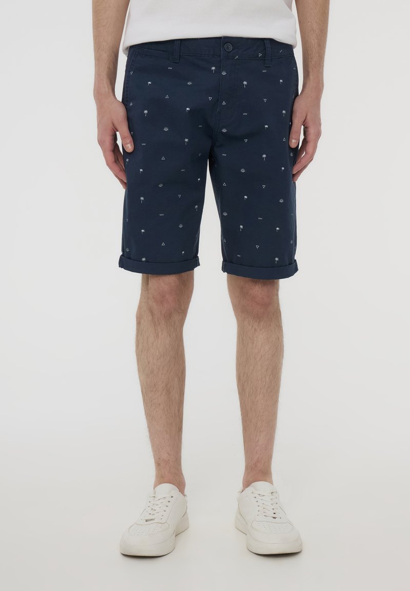 Pantaloni corti blu navy in misto cotone, con una stampa di piccoli palmi e triangoli, con orli arrotolati e chiusura con bottone.