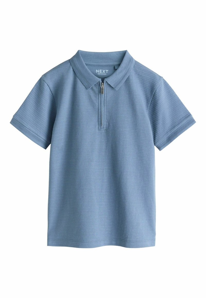 Világoskék pólóing, cipzáras gallérral, rövid ujjú és textúrált anyagból készült. Klasszikus gallérral és diszkrét bordázott részletekkel rendelkezik.