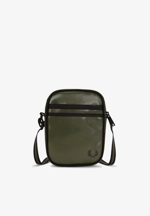 Pequeño bolso bandolera rectangular verde con ribete negro, correa ajustable, cierre de cremallera y un sutil logo de corona de laurel negra en la parte inferior derecha.