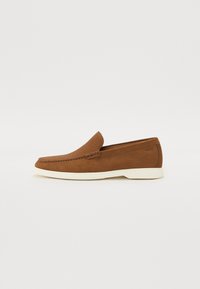 Loafere din piele maronie cu un model texturat, talpă exterioară albă și un design minimalist. Prezintă o cusătură pe partea superioară.