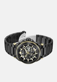 Czarny zegarek ze stali nierdzewnej z złotymi akcentami, szkieletową tarczą i regulowanym bransoletem. Posiada wyraźne znaki godzinowe i fakturowane wykończenie.