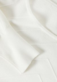 Hvid sweater med et tekstureret mønster, ribbede manchetter og en glat finish. Materialet virker blødt og let.