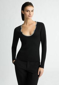 Maglietta nera a maniche lunghe con scollatura a V profonda decorata con un bordo di strass a scallop. Il tessuto presenta una texture liscia e aderente.