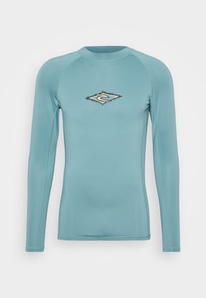 T-shirt de surf à manches longues en bleu clair, avec un logo en forme de diamant aux accents noirs et dorés. Tissu lisse et extensible.