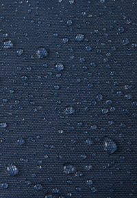 Wodoodporny granatowy materiał o fakturowanej powierzchni, prezentujący krople wody w różnych rozmiarach na swojej wytrzymałej tkaninie.