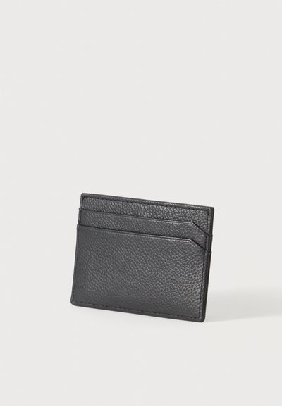 Porte-cartes en cuir noir texturé avec trois fentes horizontales pour cartes sur un fond clair.