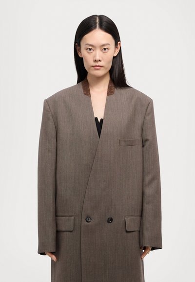 Hnedý oversize blazer z vlnenej zmesi s hlbokým V-výstrihom, dvojitými gombíkmi a kontrastným golierom. Štruktúrovaný strih s detailom prednej vrecka.