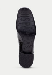 Suela de zapato de cuero negro con una superficie texturizada, con grips circulares y la marca grabada "HISPANITAS". Fabricado en España, talla 37.