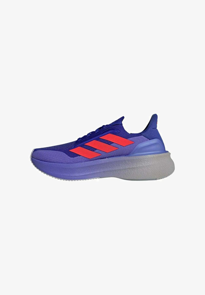 Baskets de sport violettes avec des accents bleus, dotées de trois rayures rouges sur le côté, d'une tige texturée et d'une semelle grise épaisse.