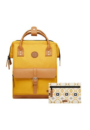 Yellow canvas backpack with brown leather accents, top handle, and magnetic flap. Includes a patterned white pouch with geometric designs.