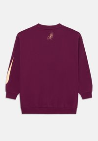 Felpa girocollo color mogano con maniche lunghe. Presenta un logo dorato sul retro e un leggero accento sulla manica. Realizzata in morbido materiale di cotone.
