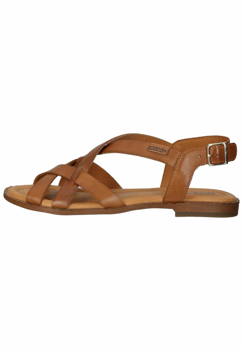 Brown leather sandal with crisscross strap design, flat sole, adjustable ankle buckle, and a textured footbed for grip.