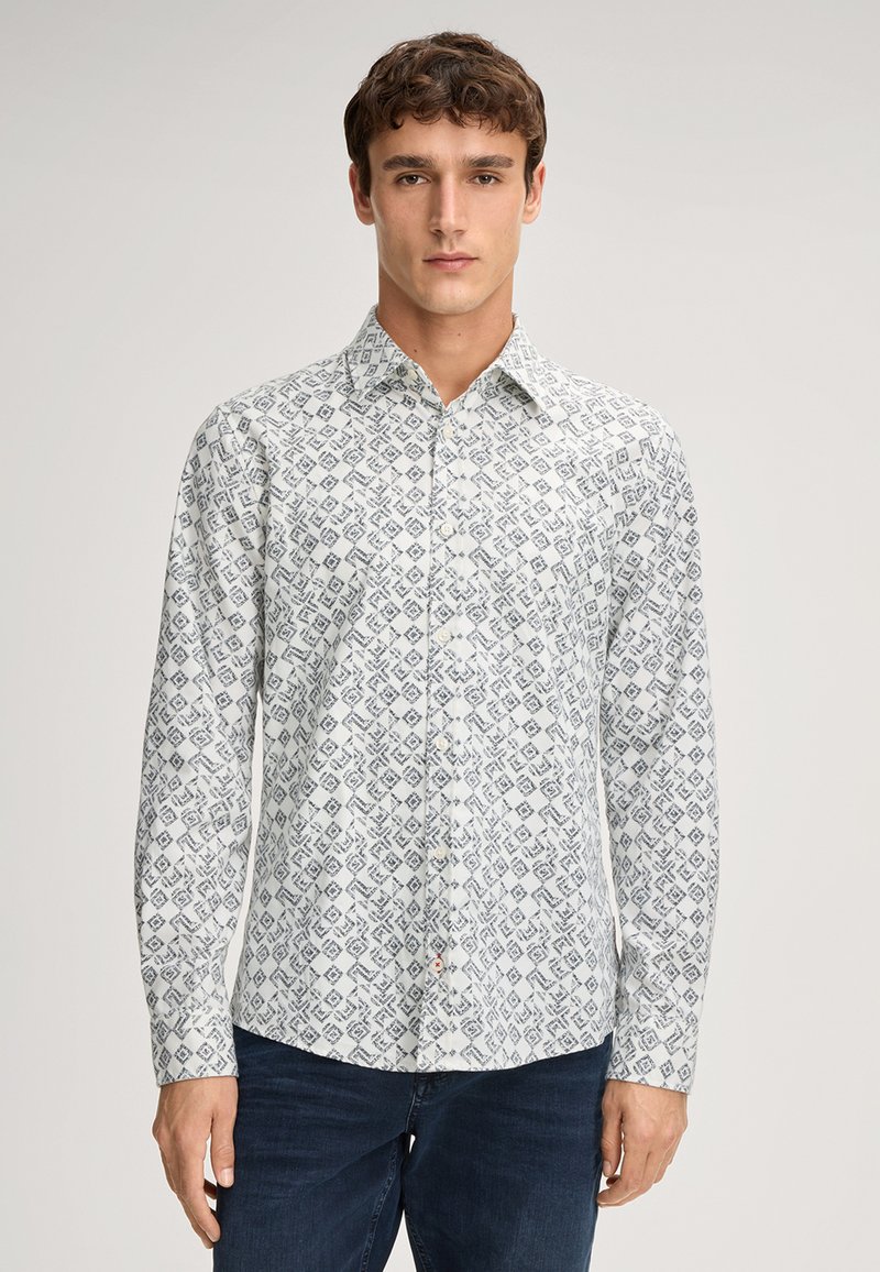 Witte overhemd met lange mouwen en een geometrisch blauw patroon, met knopen aan de voorkant en een kraag. De stof lijkt glad en lichtgewicht te zijn.
