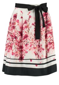 Jupe florale blanche, ornée de motifs de fleurs abstraites roses et rouges. Taille noire avec un nœud et des rayures horizontales noires contrastantes.