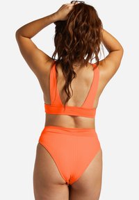 Bikini set s vysokým pásom v jasne oranžovej rebrovanej látke. Športový dizajn so širokými ramienkami a zapínaním na chrbte. Hladká textúra bez vzorov.