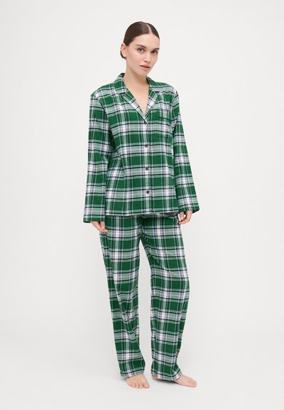 Green plaid pajama set with white accents; button-up long-sleeve top and matching wide-leg pants, made of soft fabric.