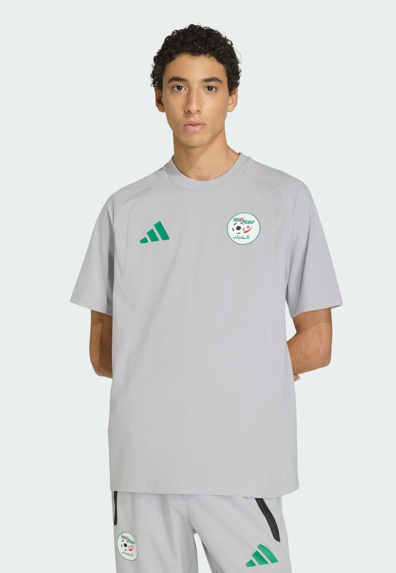 Szary sportowy trykot z krótkimi rękawami, z zielonym logo i trzema zielonymi paskami na lewym ramieniu. Wykonany z gładkiej tkaniny.