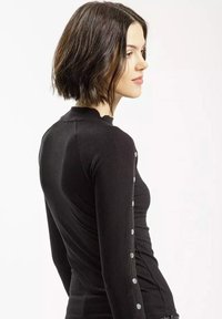 Czarny prążkowany top z długim rękawem o wysokim dekolcie, z metalowymi guzikami po lewej stronie, dopasowany krój i gładka faktura.