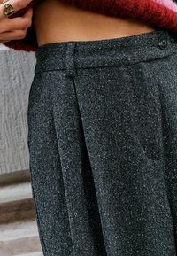 Grijze eenvoudig gestructureerde broek met een subtiele gesprenkeld patroon, met plooien, een standaard tailleband en een enkele knoopsluiting.