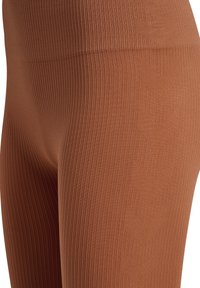 Braune gerippte Leggings mit Chevron-Muster, elastischem Bund und einer glatten, dehnbaren Textur. Ideal für bequemen Tragekomfort.