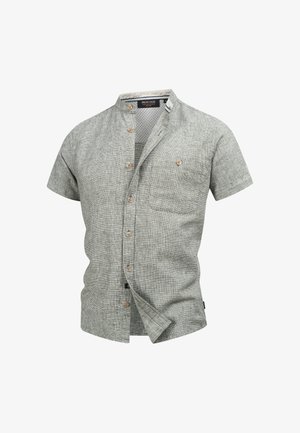 Camicia a maniche corte grigia chiara a quadri con colletto alla cinese e una tasca sul petto, parzialmente sbottonata.