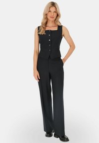 Czarny kamizelka w paski z kwadratowym dekoltem i trzema guzikami, połączona z szerokimi spodniami w tym samym kolorze i czarnymi butami. Gładka faktura tkaniny.