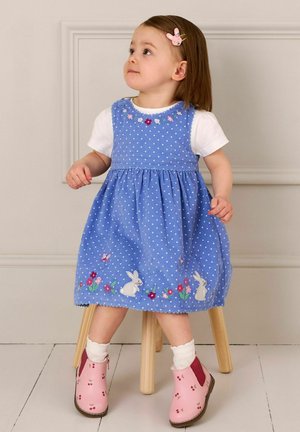 Rochie bleu cu buline, decorată cu broderie florală și detalii cu iepurași, asortată cu botoșei roz până la glezne, împodobiți cu cireșe, și șosete albe.