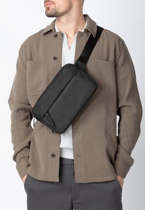 Black crossbody bag with a rectangular shape, made of textured material; features a zipper closure and an adjustable strap.